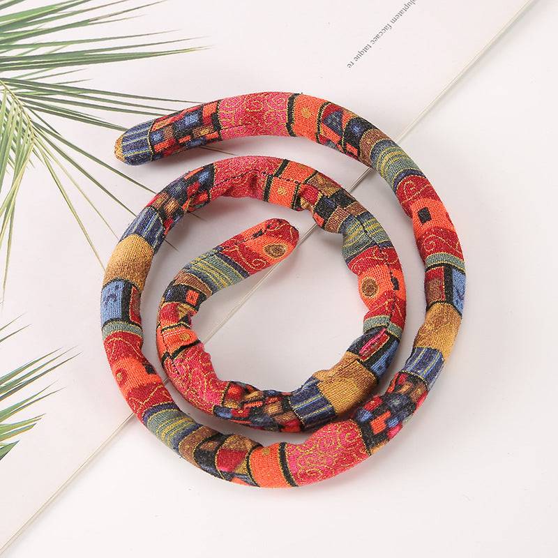 Red and gold moldable hair tie with a vibrant pattern. Flexible and secure, perfect for styling locs, dreadlocks, and braids.