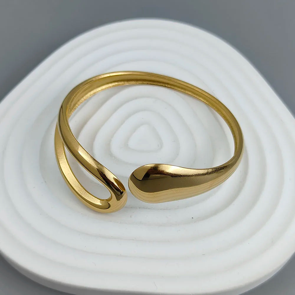 Adjustable gold-plated cuff ring with modern minimalist open loop design on a gray background