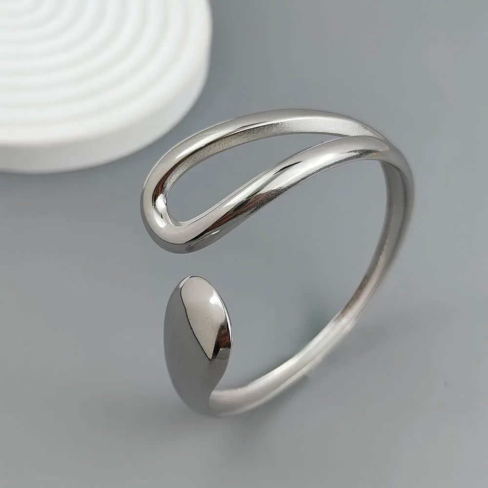 Adjustable gold-plated cuff ring with modern minimalist open loop design on a gray background