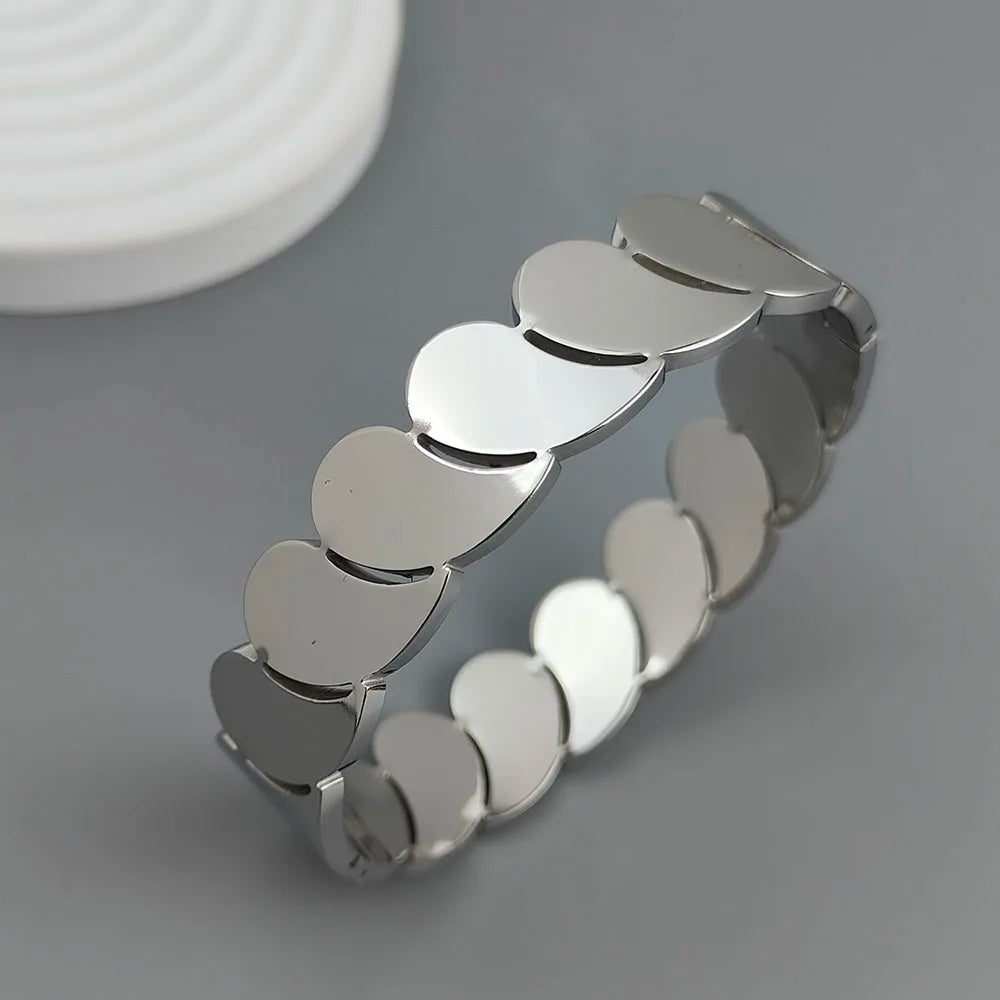 Silver cuff bracelet with polished heart-shaped links on a gray background