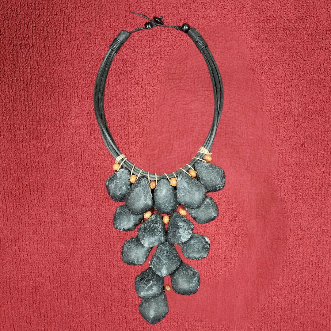 Charcoal Drift Choker featuring handcrafted black stone-like pendants with wooden bead accents on a multi-strand black cord. Unique African-inspired statement necklace.