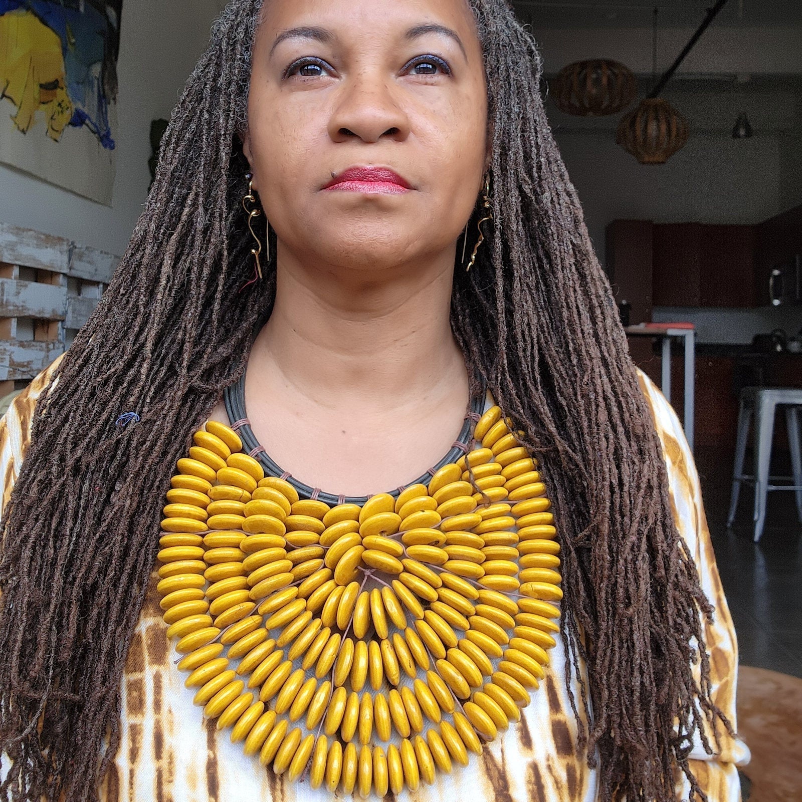 Handmade Citrine Cascade Collar worn by a model, showcasing its intricate yellow wooden bead design. A perfect accessory for bold and elegant outfits.