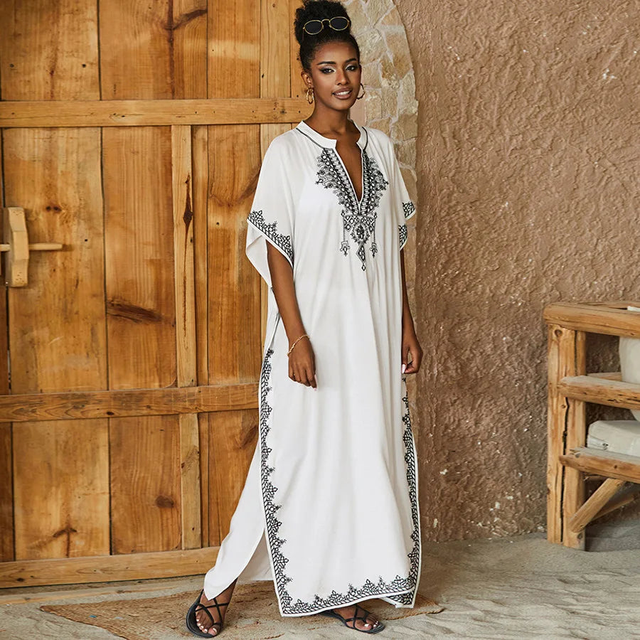 Stylish white kaftan with black embroidery, loose-fitting and breathable, perfect for resort wear or elegant lounging.