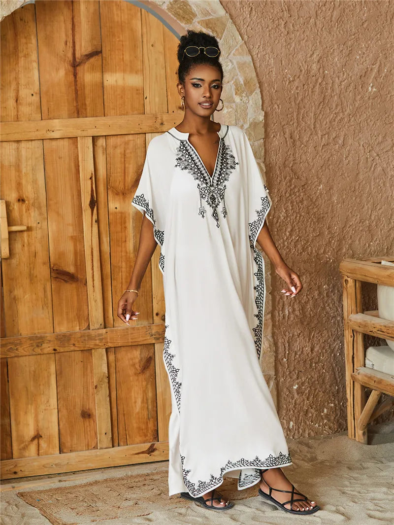 Elegant white kaftan with intricate black embroidery, a relaxed fit, and lightweight fabric, ideal for warm-weather occasions.