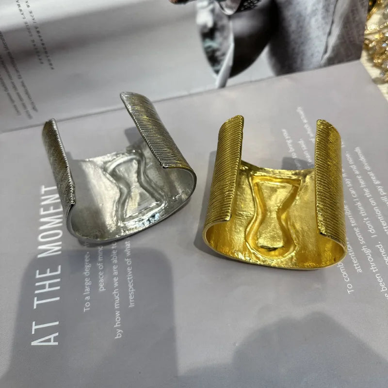 Inside view of exaggerated gold and silver keyhole hair cuffs showing smooth metallic interior.