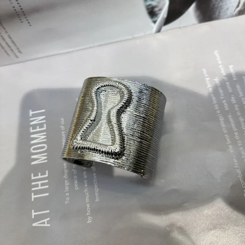 Silver keyhole hair cuff with wide exaggerated shape and textured metallic finish.