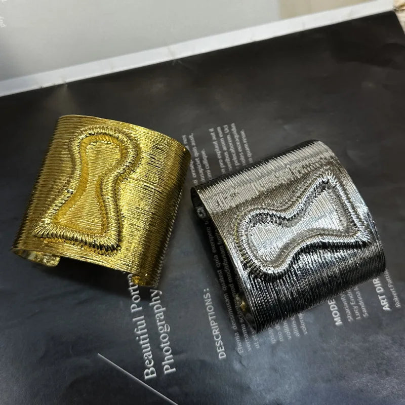 Gold and silver keyhole hair cuffs shown from top angle, highlighting metallic sheen and bold design.