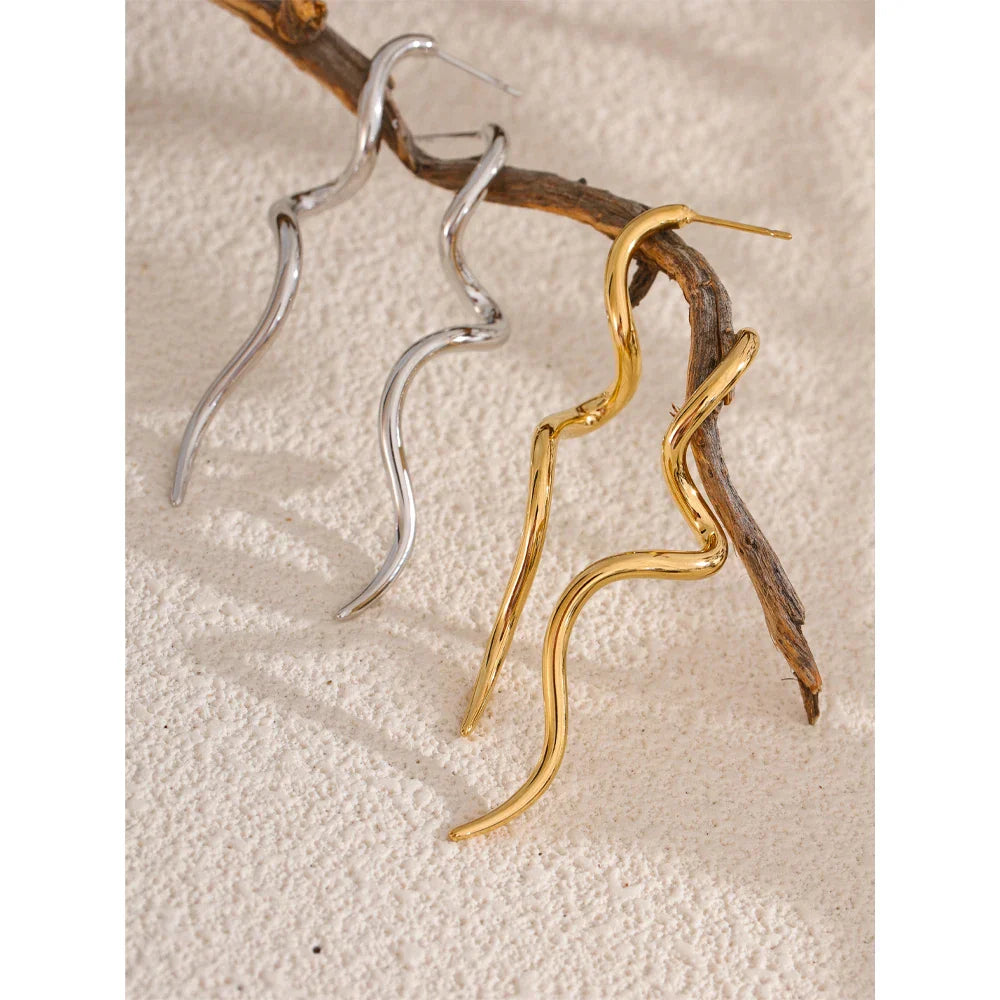 Gold and silver flowing metal geometric long stud earrings hanging on a branch, highlighting their artistic and modern appeal.
