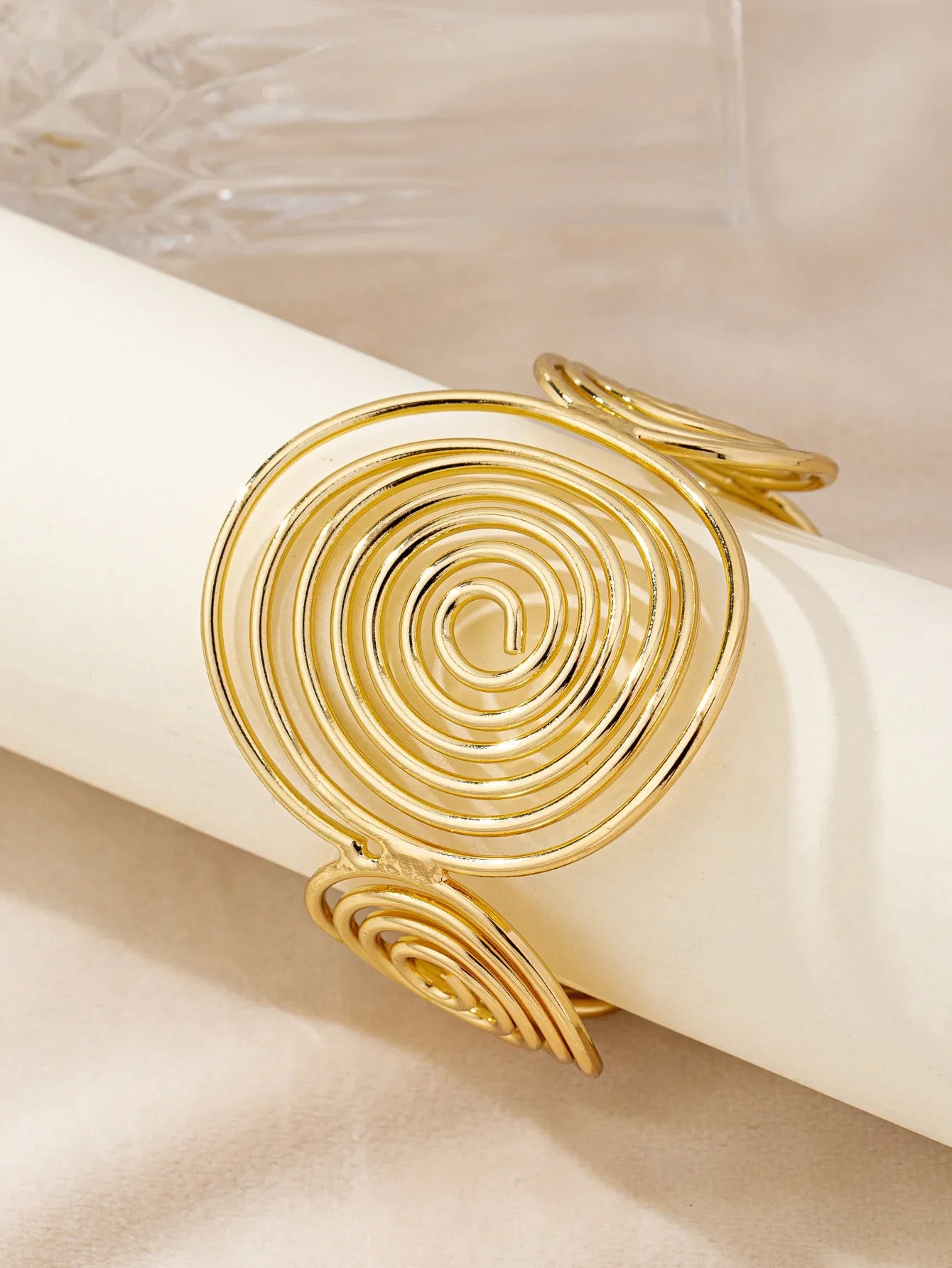 Gold swirl hair cuff shown at an angle, featuring a large central spiral and two side spirals.