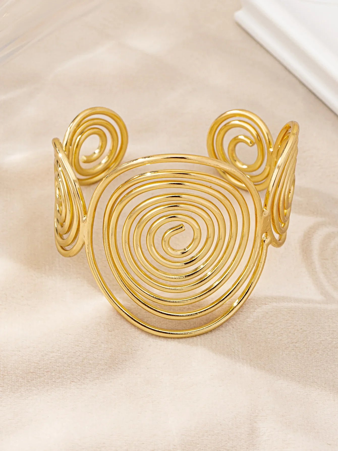 Gold swirl hair cuff shown at an angle, featuring a large central spiral and two side spirals.