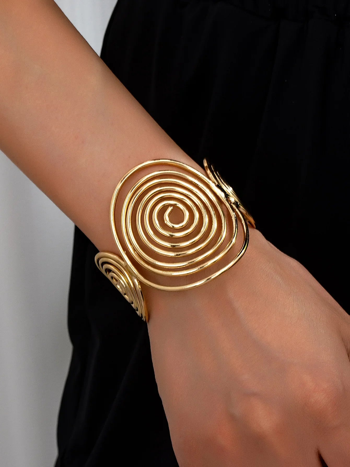 Gold swirl hair cuff with elegant spiral design, styled on wrist to show fit and shine.