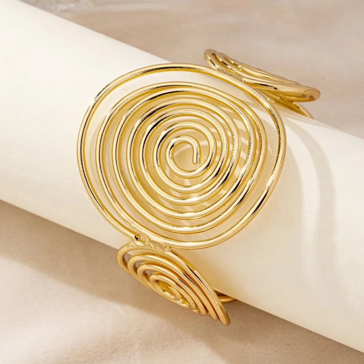 Gold swirl hair cuff with multiple swirling spiral details, viewed from a side angle.