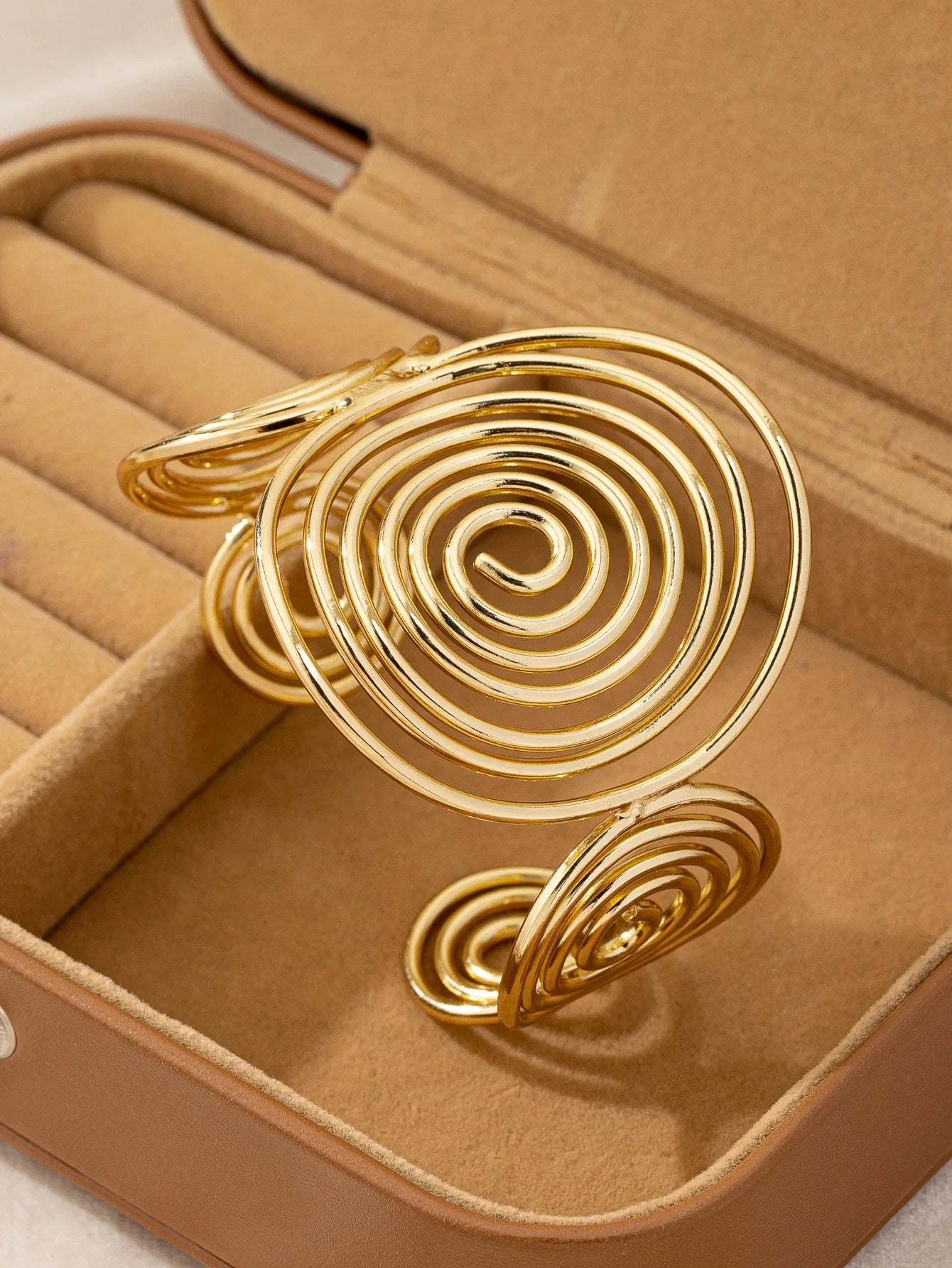 Gold swirl hair cuff with shiny gold finish, placed inside a jewelry box for display.