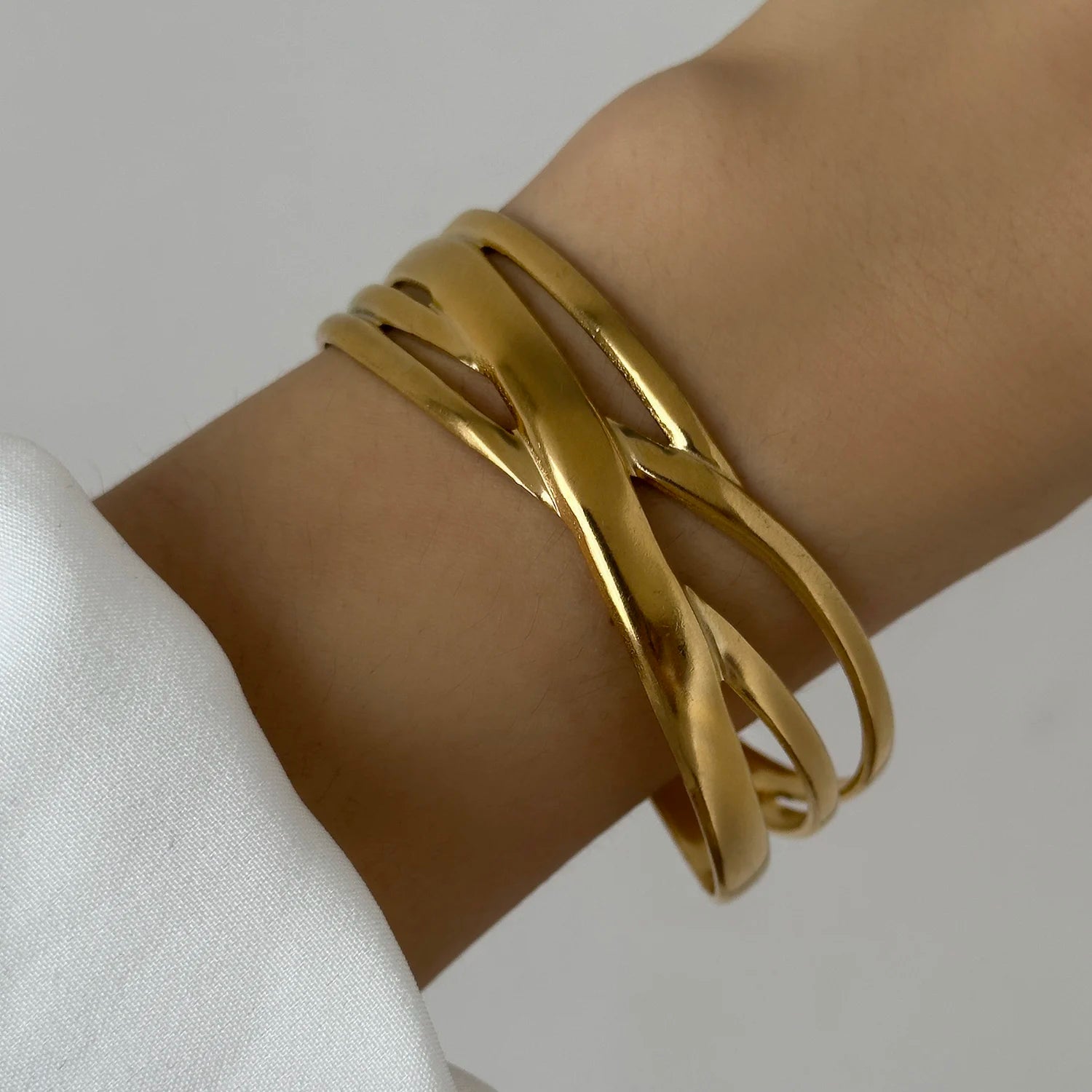 Close-up of a gold twisted cuff bracelet with overlapping bands, creating a modern and elegant statement look