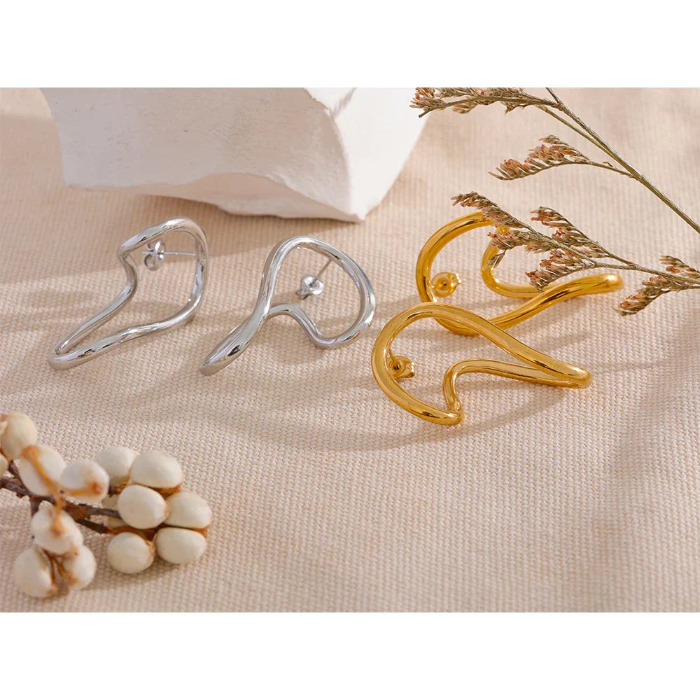Gold and silver twisted stud earrings displayed on a neutral fabric background. Stylish and creative earrings for women with a vintage touch.