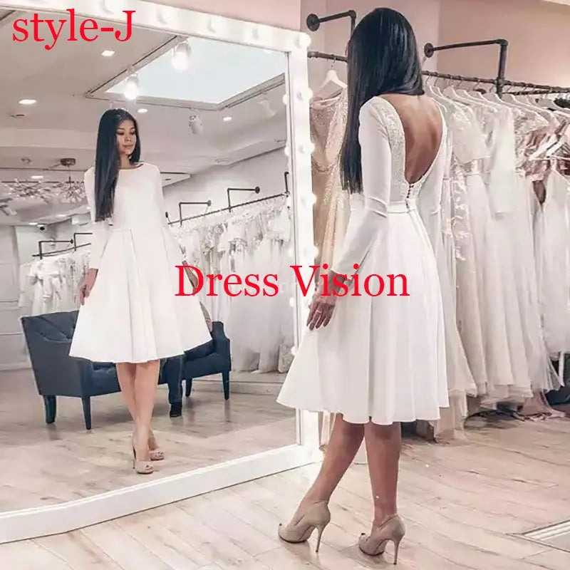 White midi dress with long sleeves and an open-back design, displayed in a bridal boutique. A timeless and elegant wedding dress.