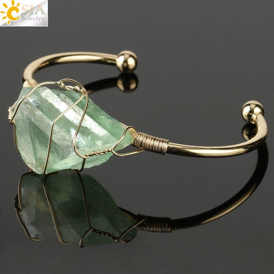Gold-tone copper bracelet featuring a wire-wrapped irregular green crystal quartz centerpiece.