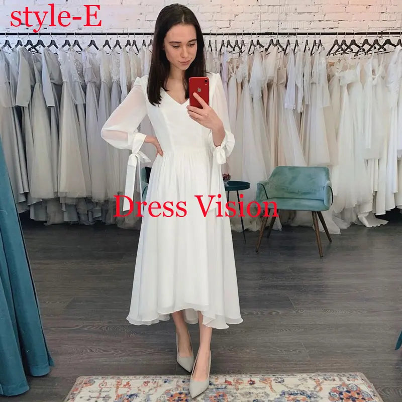 White midi dress with long sleeves and a V-neckline, displayed in a bridal boutique. A simple and elegant wedding dress.