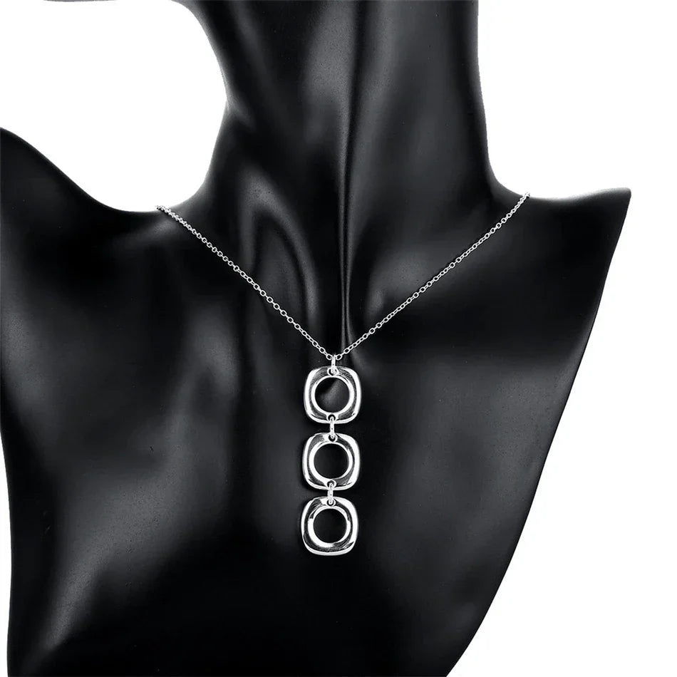 Geometric sterling silver pendant necklace displayed on a black mannequin bust. A statement jewelry piece for modern fashion lovers.