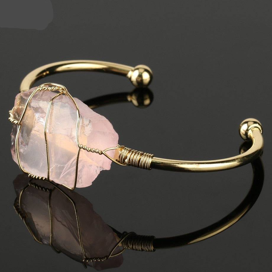 Gold-tone copper bracelet featuring a wire-wrapped irregular rose quartz crystal centerpiece.