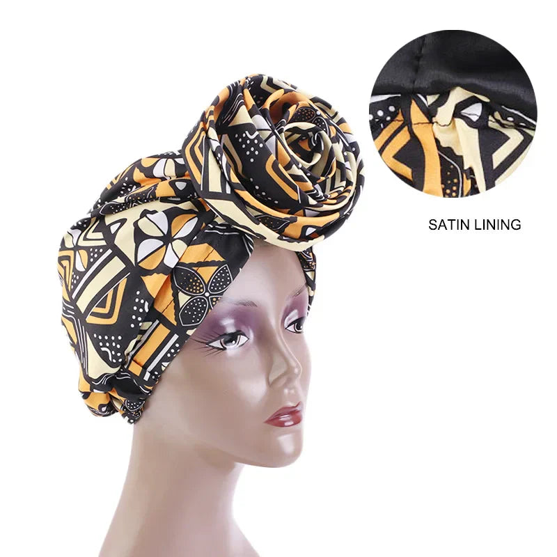 Black and gold Ankara head wrap with satin lining for hair protection. Features an elegant African-inspired print.