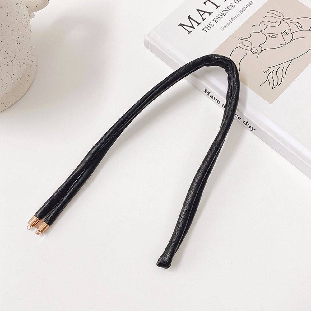 Black non-damaging ponytail holder for locs placed on a book. Ideal hair tie for dreadlocks, braids, and sisterlocks with gold-tone tips.