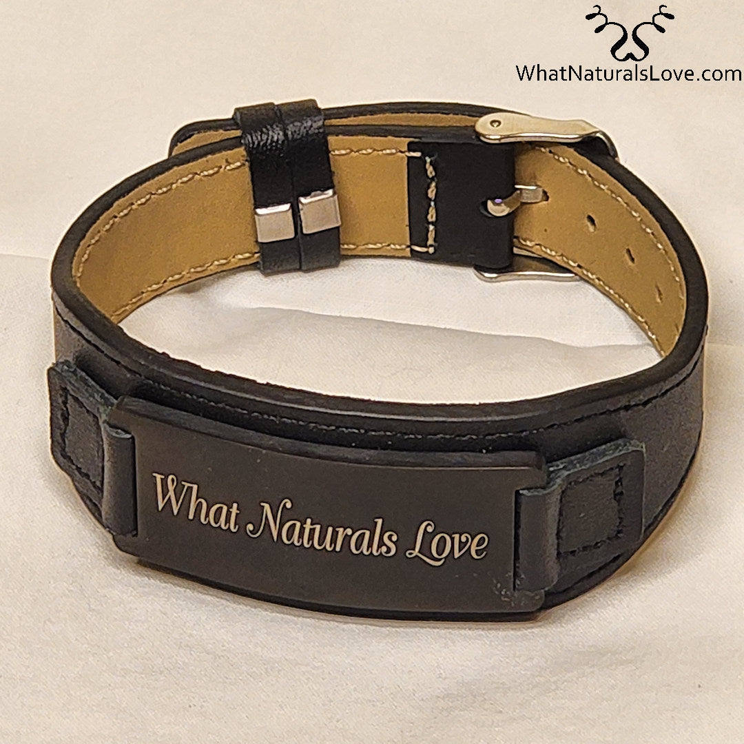 Adjustable What Naturals Love Hair Tie with a black leather strap and engraved metal plate. Perfect for securing natural hair with style.