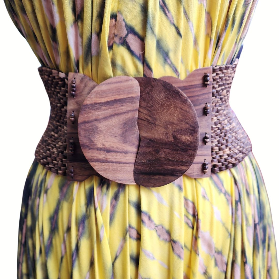 Vintage woven fabric belt with a large wooden buckle, worn over a yellow patterned dress. Stylish and bohemian accessory for women.