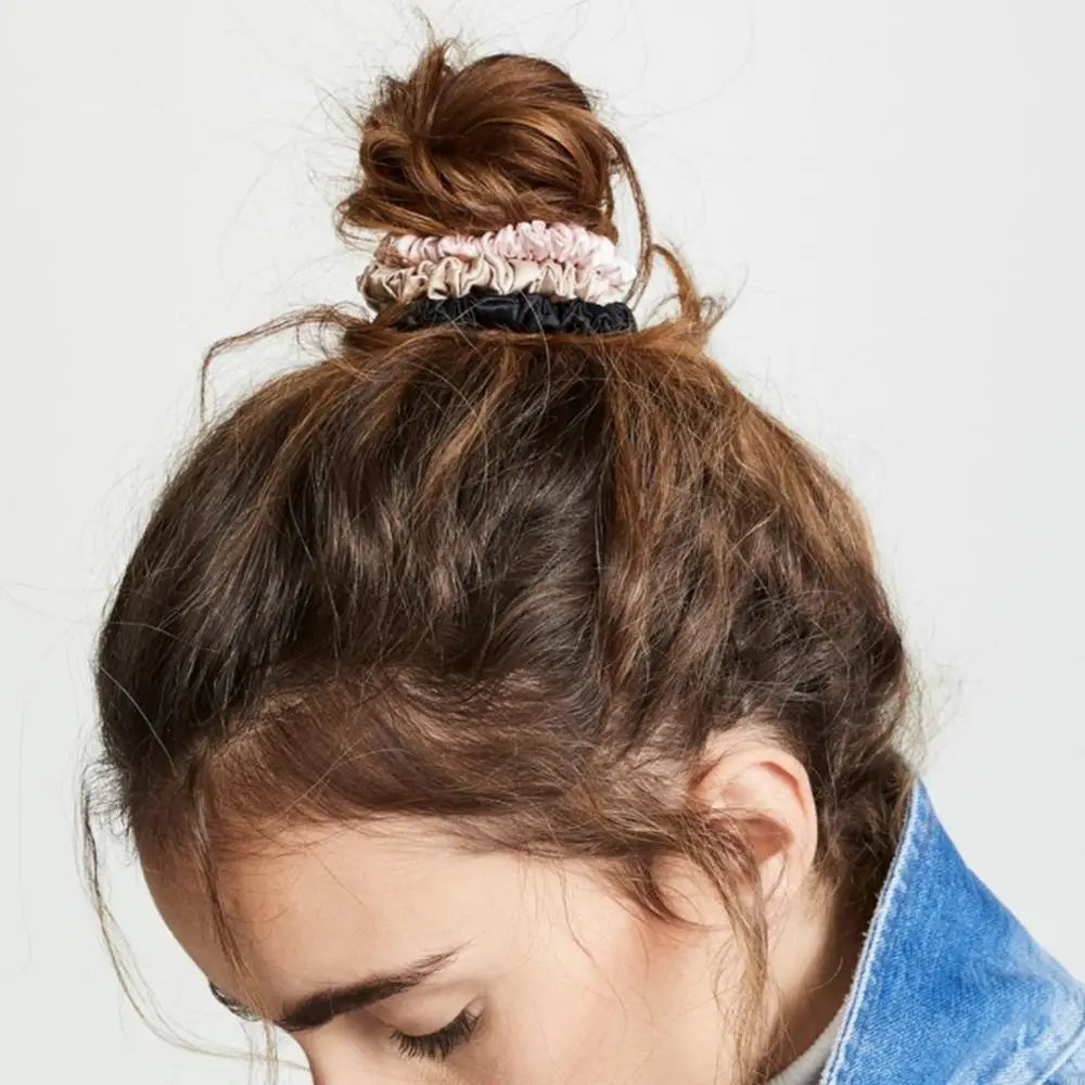 Top bun hairstyle secured with stacked mulberry silk elastic hair bands in pink and black. Soft, snag-free hold for all-day comfort.