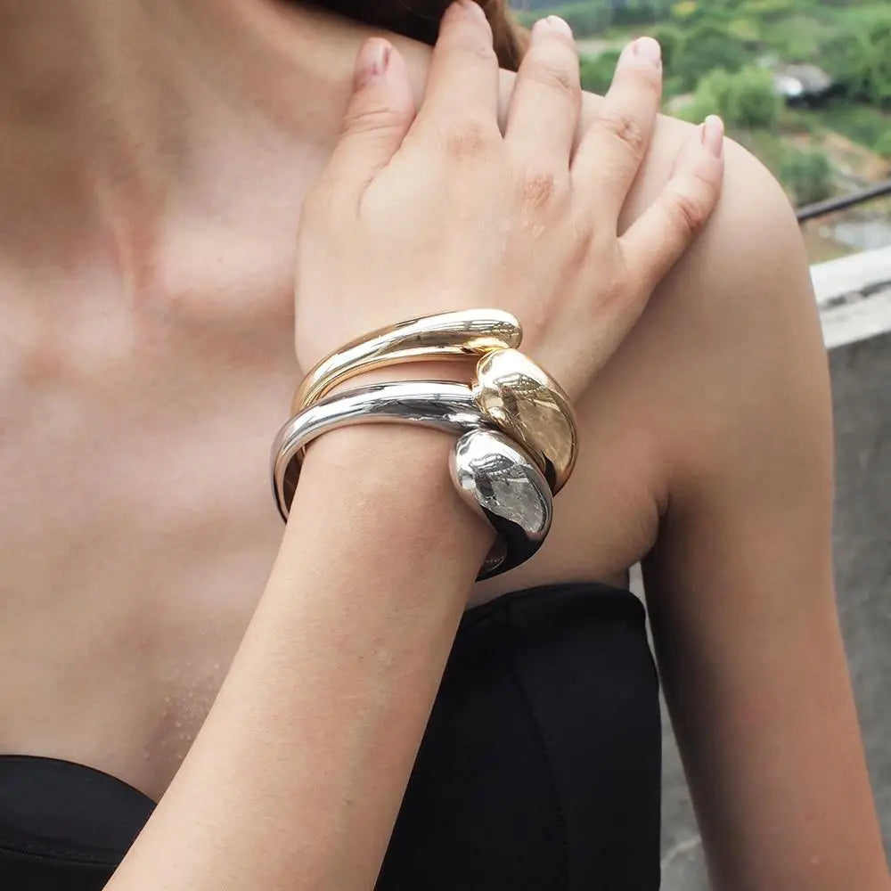 Model wearing multiple sleek loc cuffs in gold, silver, and black. A fashionable and non-damaging hair accessory for special occasions.