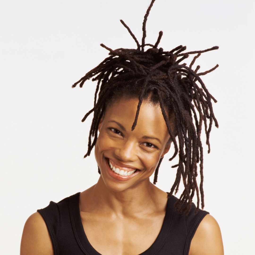 Smiling woman with styled human hair loc extensions, showcasing 0.4 cm thick natural dreadlocks for a trendy look.
