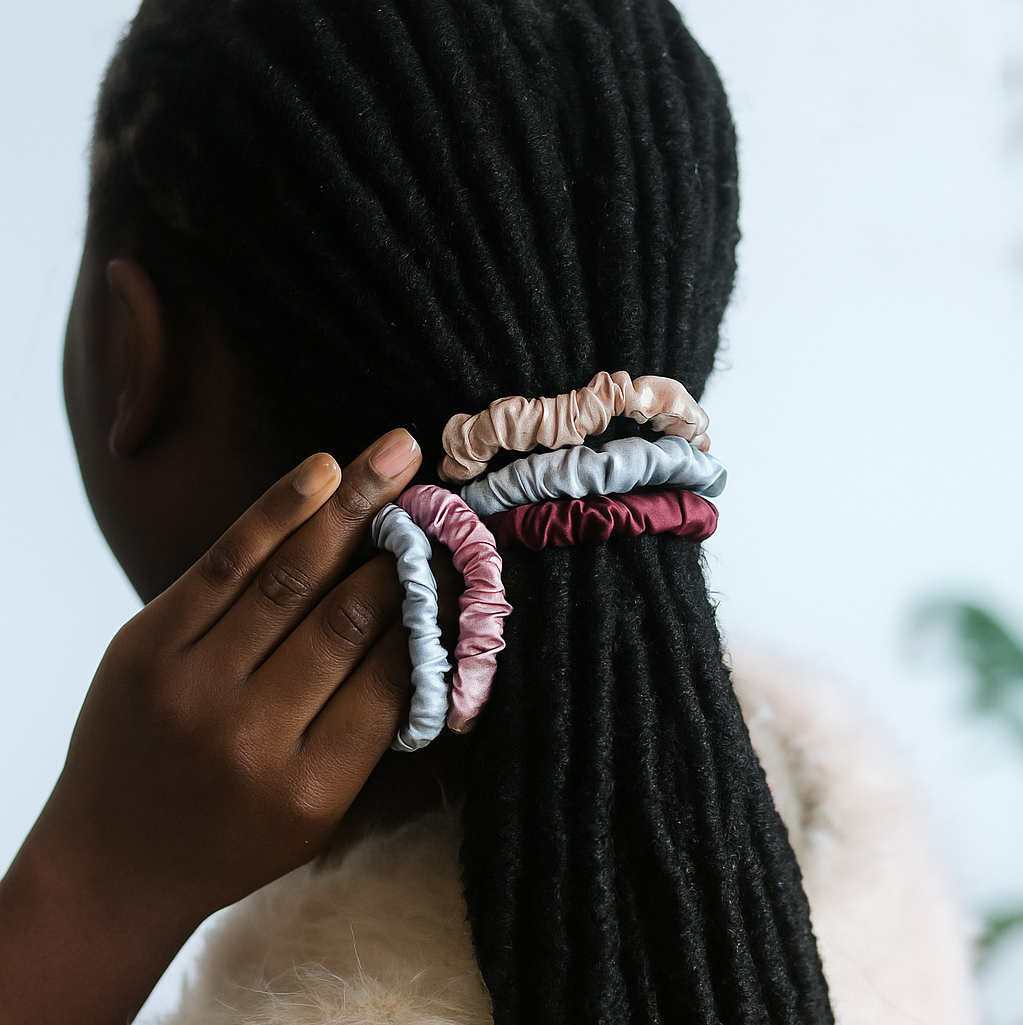 Person with long locs using multiple Mulberry Silk Hair Elastics in assorted colors. Perfect for natural hair and moisture retention.