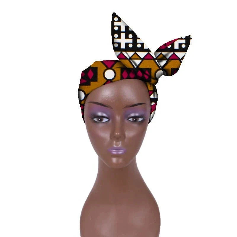 African hair bow band headdress in brown, black, and red geometric patterns, styled on a mannequin. A bold and cultural fashion piece.