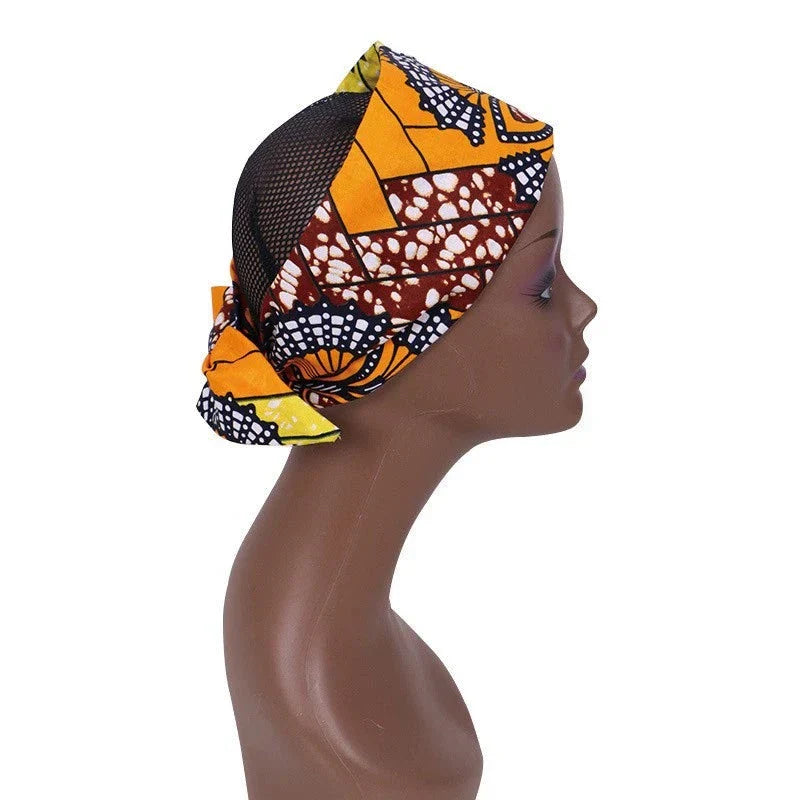 Side view of an African hair bow band headdress in orange and brown patterns, displayed on a mannequin. A vibrant and stylish headwrap.
