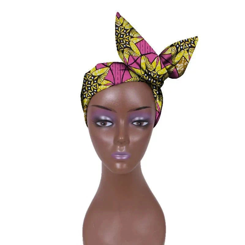 Pink and yellow African hair bow band headdress with floral patterns, styled on a mannequin. A chic and elegant head accessory.