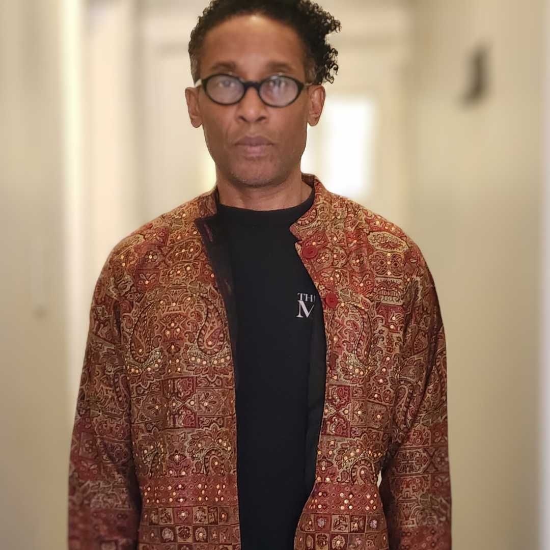 Close-up of paisley embroidered Indian jacket with open front, revealing a black inner shirt. Elegant and artistic outerwear with cultural charm.