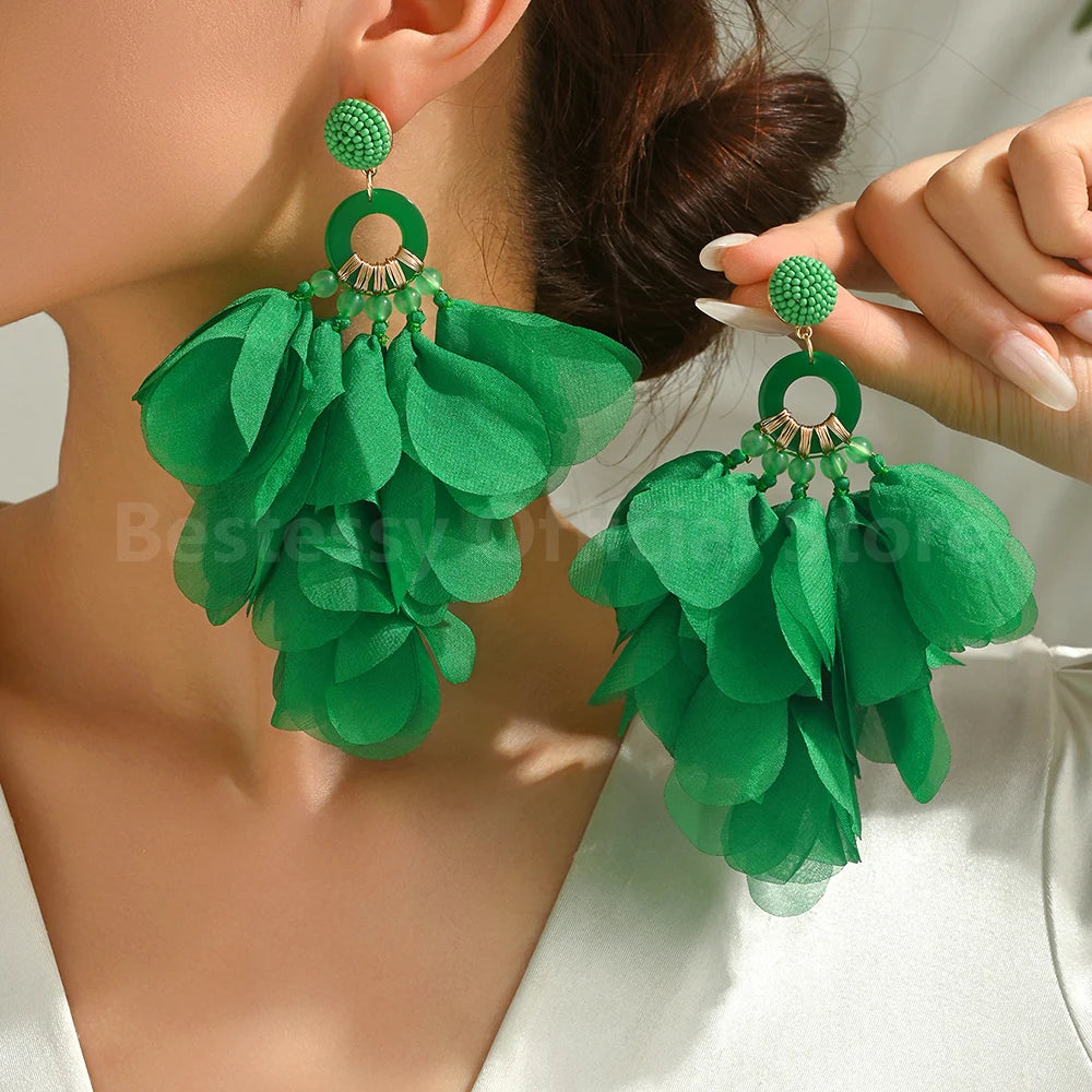 Green floral earrings being worn by a person on a white background