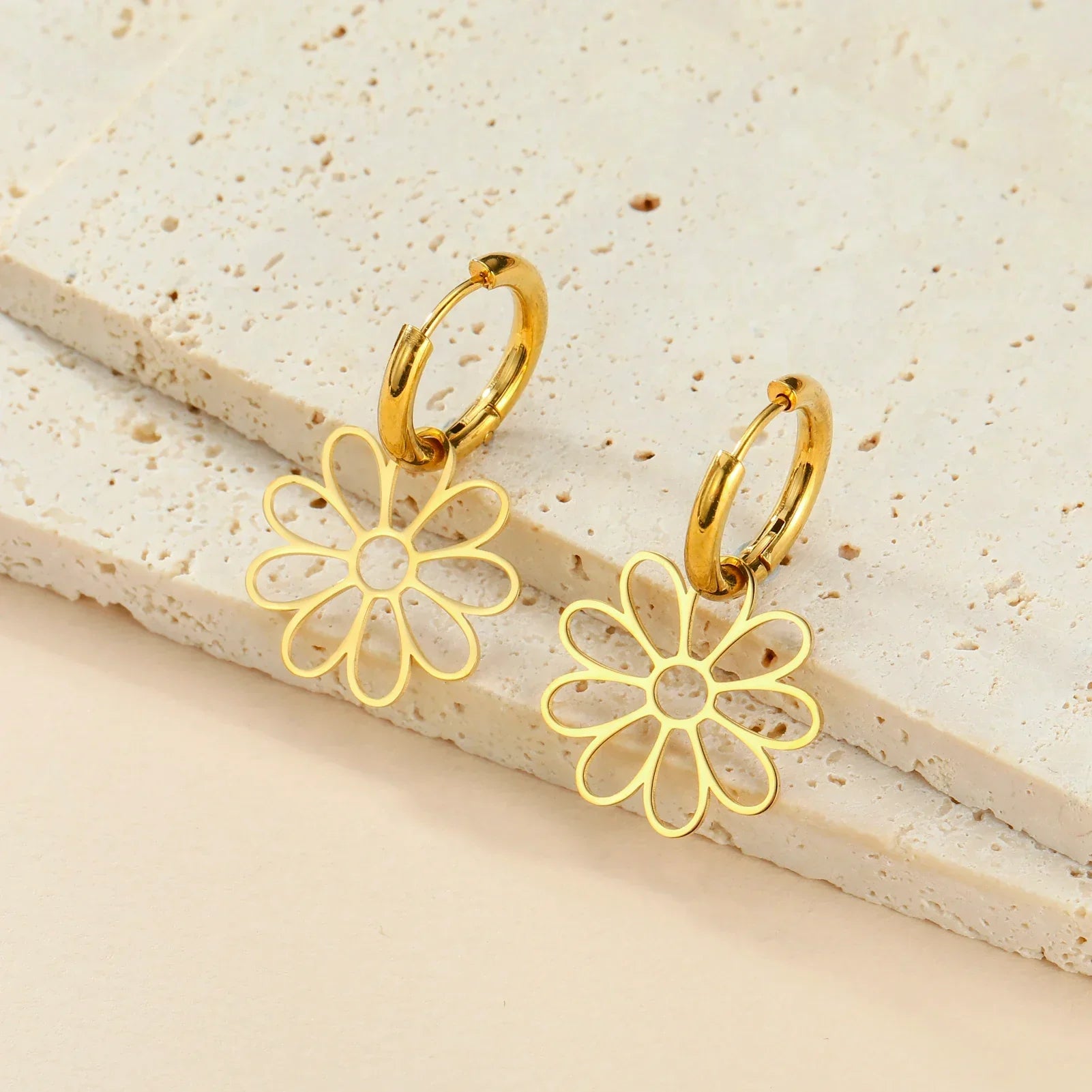 Gold flower hoop earrings with a single floral charm. Minimalist and stylish jewelry piece perfect for casual and formal outfits.
