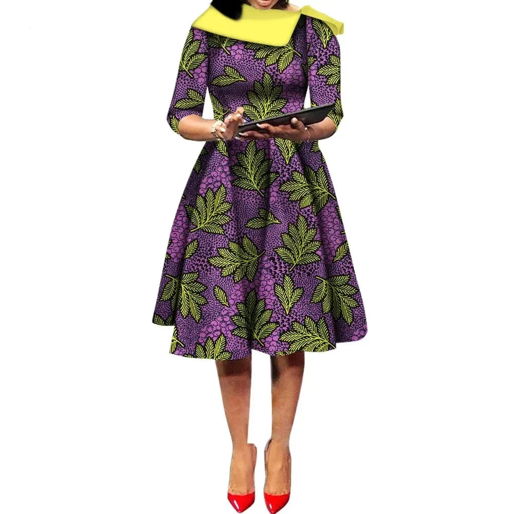 African Ankara Wax Print Midi Dress in purple with green leaf patterns, featuring a fitted waist and flared skirt.