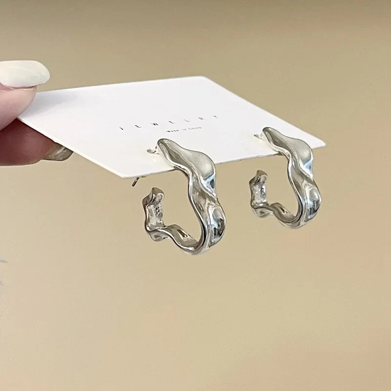 Silver-tone irregular hoop earrings displayed on a branded card. Unique and stylish modern vintage earrings for women.