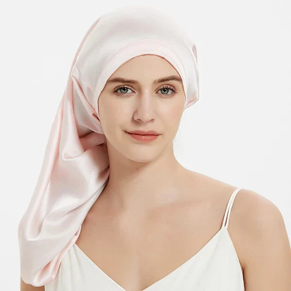 Light pink Mulberry Silk Sleep Bonnet for long hair, worn by woman. Adjustable silk headwrap for frizz-free mornings and comfort.