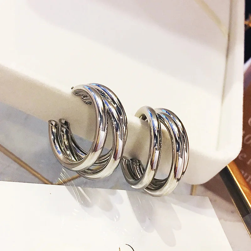 Silver-tone triple hoop stud earrings with a modern vintage aesthetic. Stylish and versatile metal earrings for women.