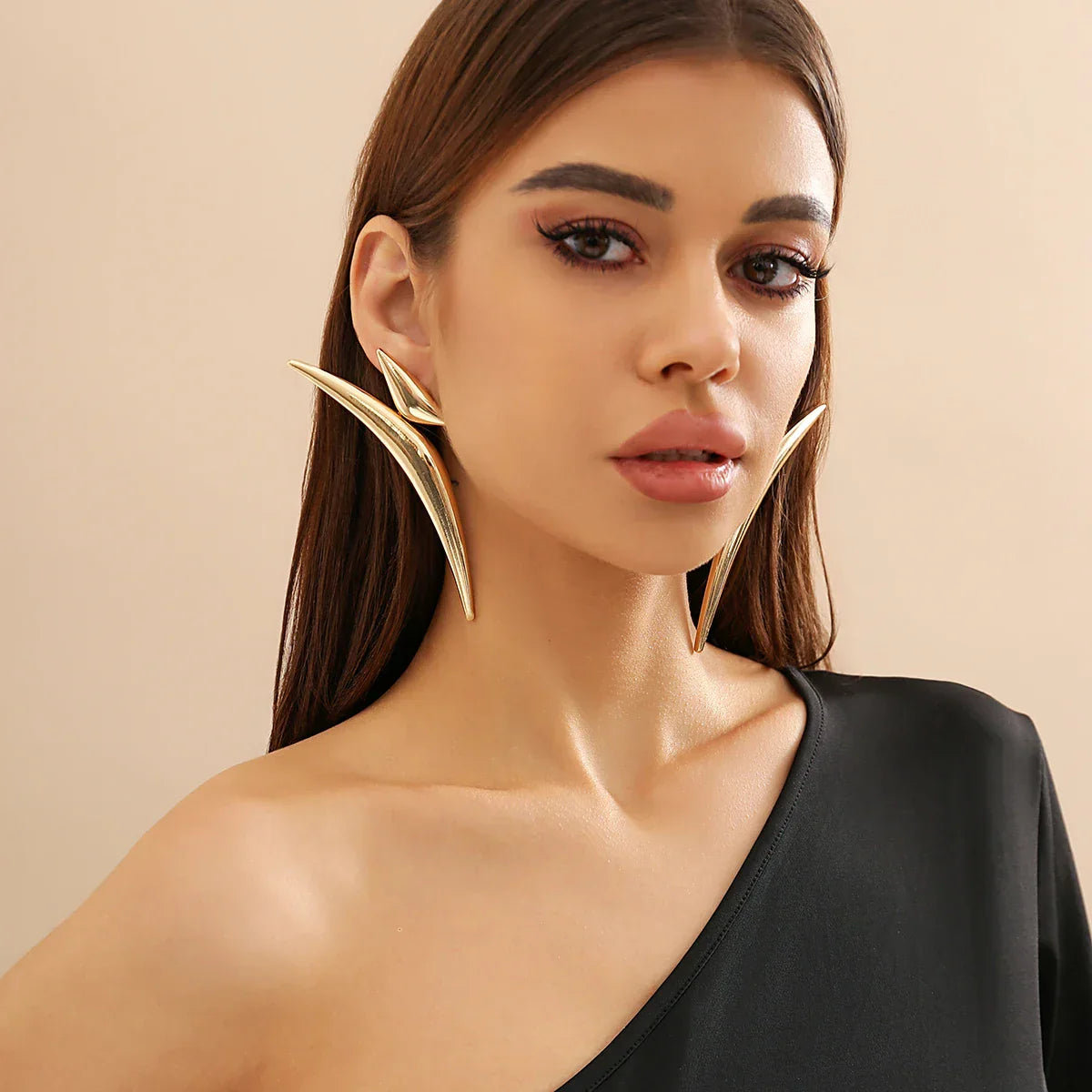 Model wearing Sleek Aeonian Ear Wings in gold-tone metal. Statement geometric earrings with a futuristic and elegant aesthetic.