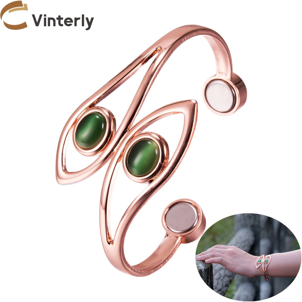 A rose gold butterfly-shaped open bangle bracelet with two green cabochon gemstones, shown on a white background with a brand logo &