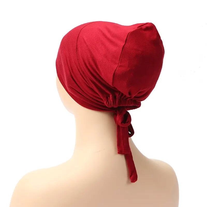 Back view of the red adjustable headwrap on a mannequin, showing the gathered elastic and tie-back design for a snug fit.