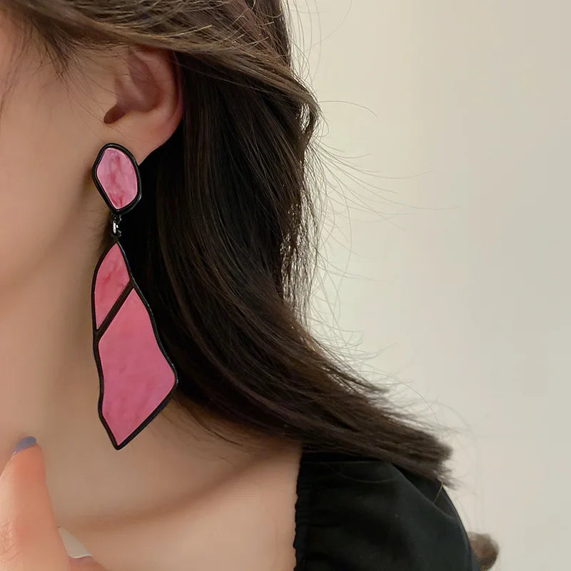 Blue Oceanic Shard Drop Earrings worn by a woman. Geometric statement earrings with a marbled texture, perfect for bold fashion statements.