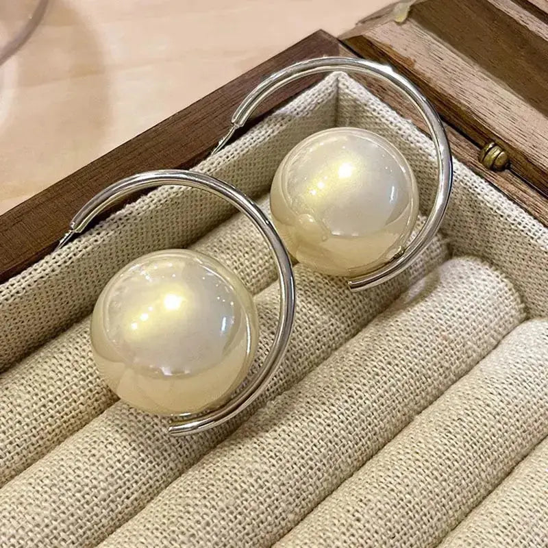 Silver hoop earrings with large pearl accents, placed in a jewelry box. A sophisticated and stylish jewelry piece.