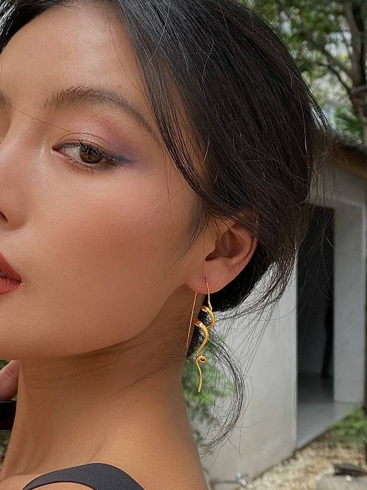 Model wearing Serenity Threader Earrings in gold, highlighting their elegant and modern design. A fashionable jewelry piece for Memorial Day 2024.