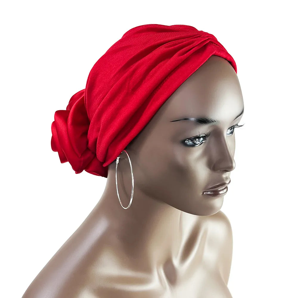 Red floral stretch bandana head wrap on a mannequin. Features a soft, stretchy fit with a decorative fabric rose at the back.