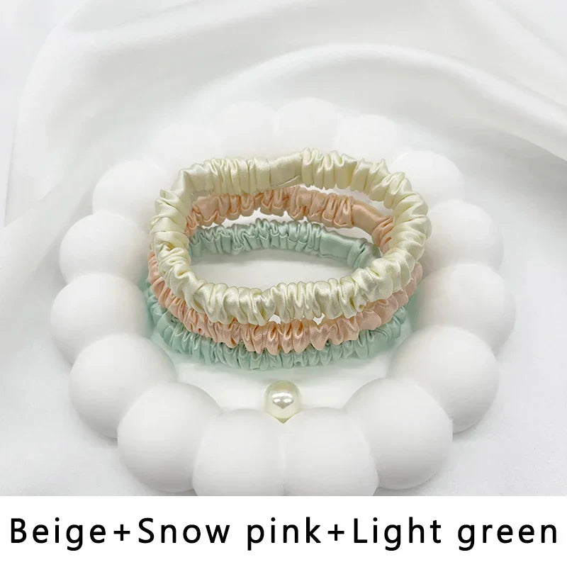 Three-piece silk hair band set in beige, snow pink, and light green. Gentle, frizz-free hold for natural hair and locs.